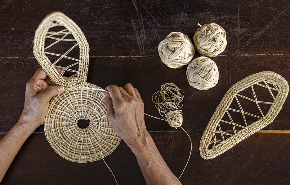 A person is working on a woven basket. Description generated by AI