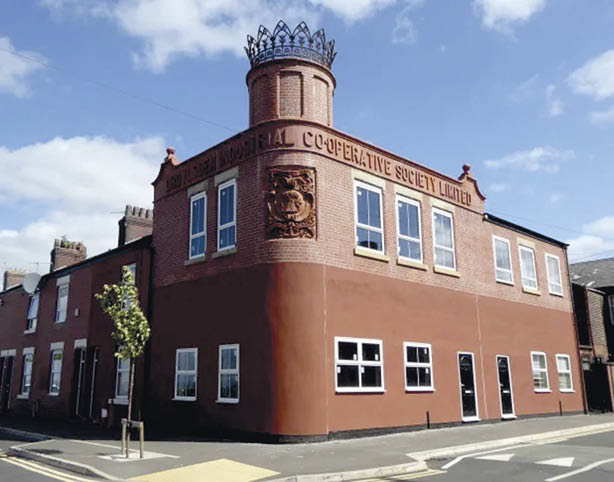 A historic brick building with a cylindrical turret topped by a decorative crown and signage reading “Industrial Cooperative Society Limited" on a street corner under a partly cloudy sky. Description generated by AI