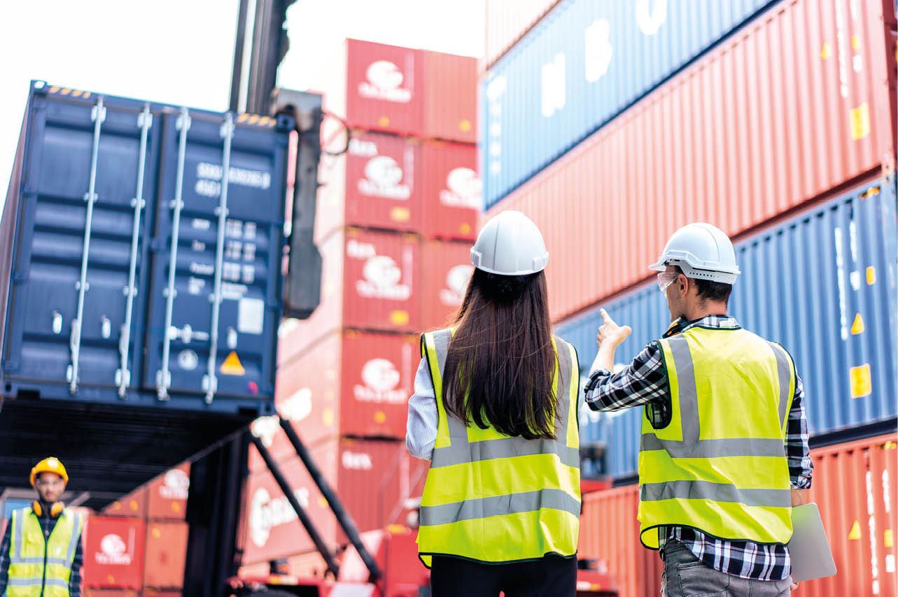 Caucasian business man and woman worker working in container terminal. Attractive engineer people processes orders and product at warehouse logistic in cargo freight ship for import export in harbor.