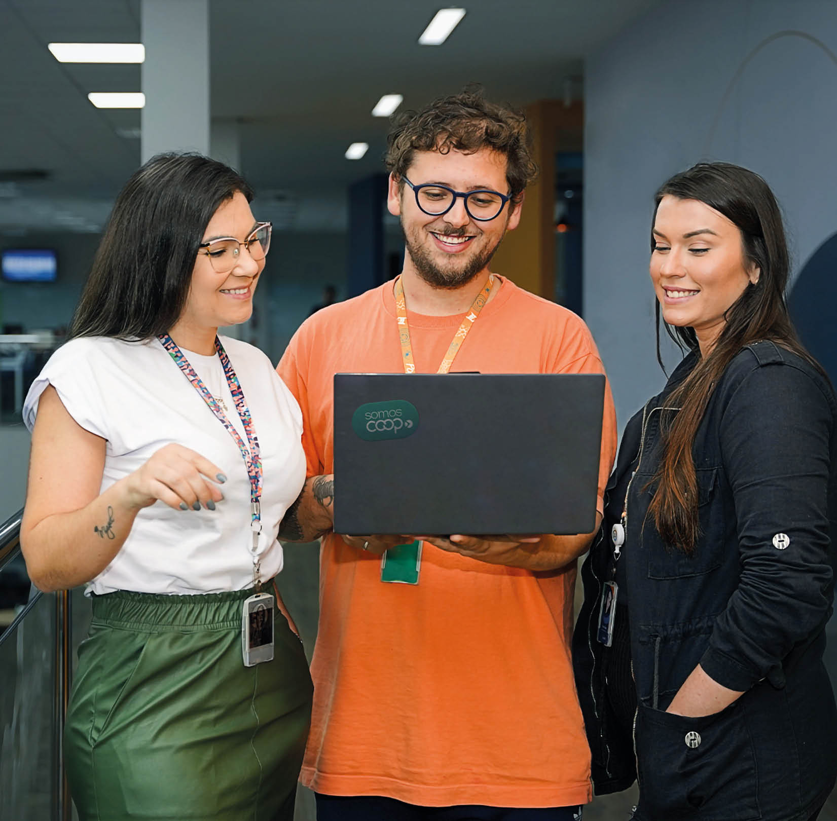 A guy and a girl in a university or high school smile as they look at the computer screen in front of them. They are sitting in a library.