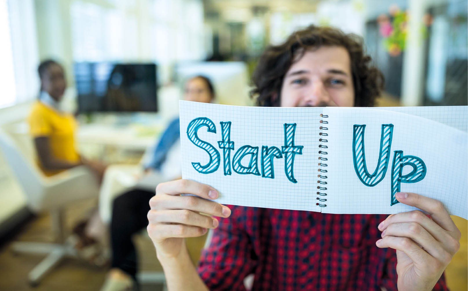 Male graphic designer holding spiral notepad with a text in office