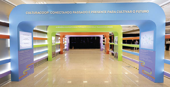 Estrutura colorida em formato de portal com textos em portugu s sobre cultura e mem ria em um ambiente interno iluminado. Description generated by AI