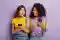 Duas mulheres com smartphones nas mãos com expressão de surpresa positiva
